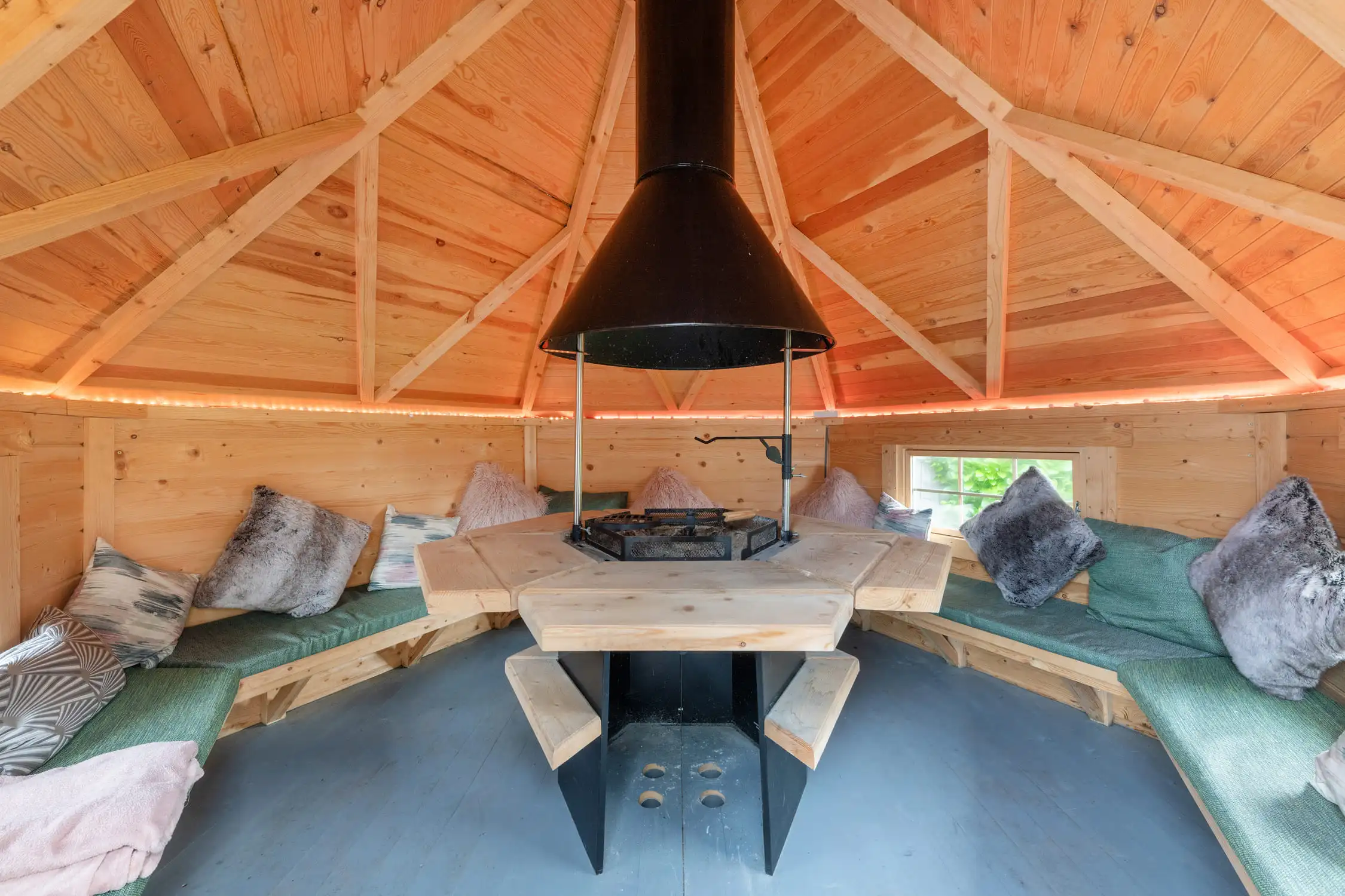 Hazelwood-Road-Great-Park-Gosforth-Newcastle-Self-Build-Home-Design-Acre-Outdoor-dining-seating-fire-pit Large self build home designed by Acre Design Newcastle on Hazelwood Road, Great Park. Outdoor seating area with large cushions and a fire pit with a black extractor hood above. A timber pitched roof on this outdoor entertaining space. Apres-ski style.