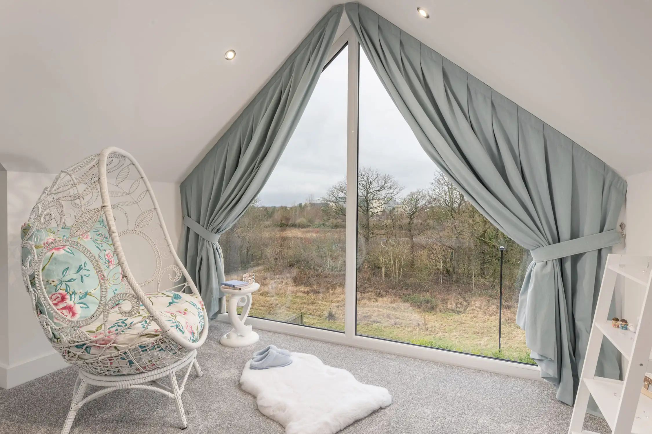 Hazelwood-Road-Great-Park-Gosforth-Newcastle-Self-Build-Home-Design-Acre-egg-chair-view-large-home Stunning egg chair looking out over woodland view through a floor to ceiling, full height apex window. The window is draped in luxurious grey curtains and there is a sheepskin rug on the floor. Modern, simple styling makes this room calm and grounded. Large self build home designed by Acre Design Newcastle on Hazelwood Road, Great Park.
