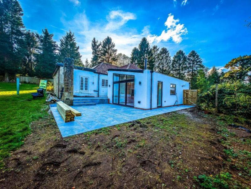 Bungalow at Hamsterley Mill transformed into a family home, with white render and large glazed doors opening onto a new patio