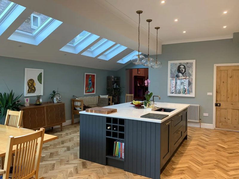 Open-plan kitchen with a dark island, rooflights and a dining area in a home in Cullercoats, North Tyneside