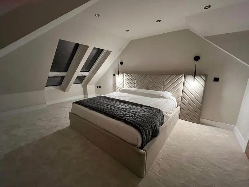 Completed loft bedroom with rooflights, a panelled headboard and soft lighting at a home in Sunderland
