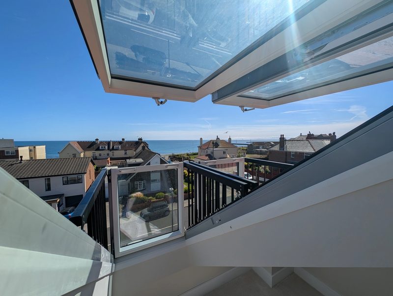 View from a loft conversion with a Juliet balcony and glazed roof towards the sea at a coastal home in Sunderland