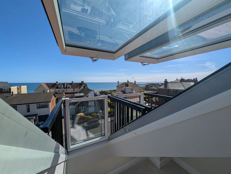 View from a loft conversion with a Juliet balcony and glazed roof towards the sea at a coastal home in Sunderland