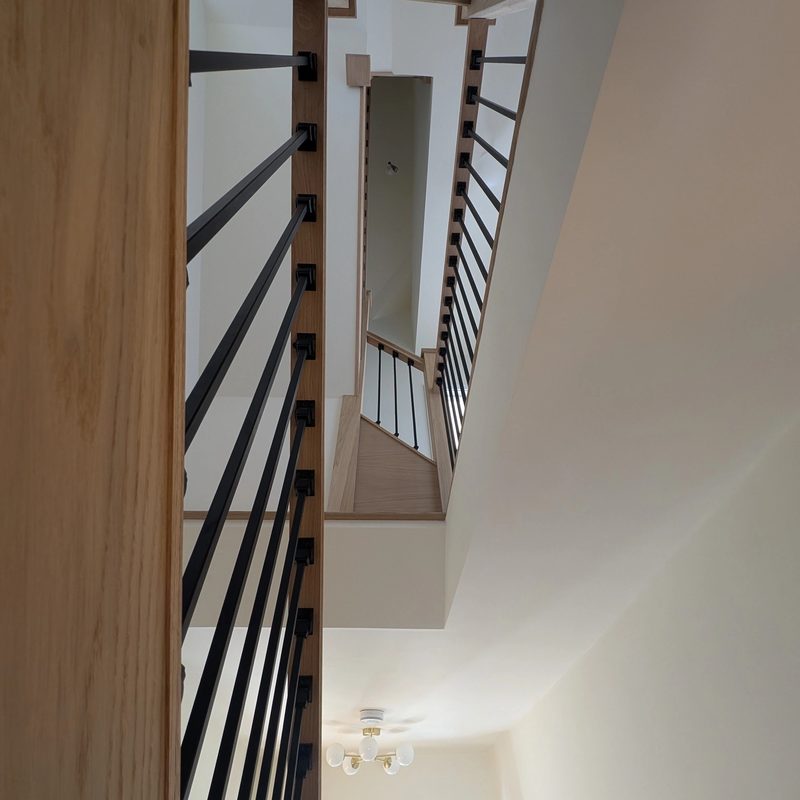 Staircase with slim metal balustrades rising through the floors of a Sunderland home with a loft conversion